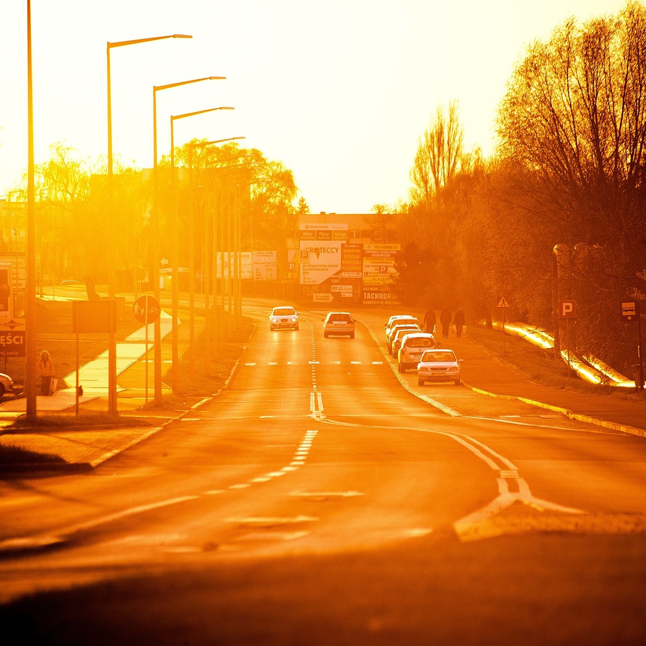 Photographie représentant une route gorgée de soleil sur laquelle circulent des voitures